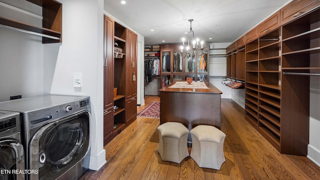 walk in closet featuring a chandelier, wood finished floors, and independent washer and dryer