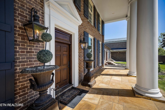 entrance to property featuring covered porch and brick siding