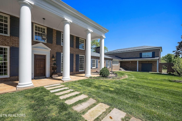 view of front of house featuring covered porch, brick siding, and a front yard