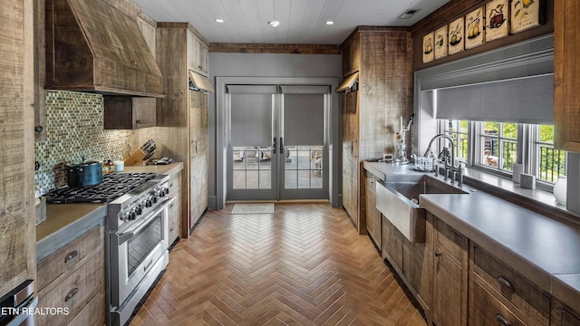 kitchen featuring custom range hood, a sink, stainless steel range, french doors, and backsplash