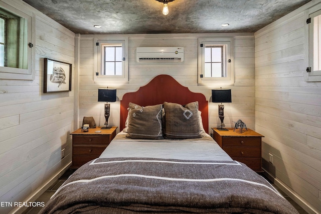 bedroom featuring wood walls, a wall mounted AC, and baseboards