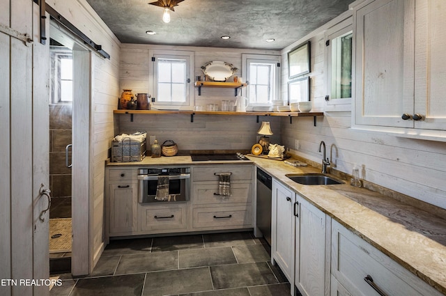 kitchen featuring wood walls, plenty of natural light, appliances with stainless steel finishes, and a sink