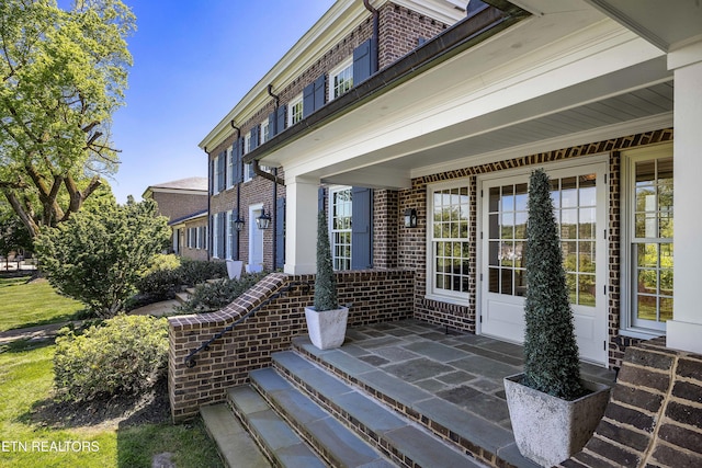 property entrance featuring a porch and brick siding