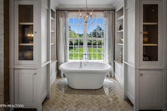 bathroom with a soaking tub, crown molding, a notable chandelier, and brick floor