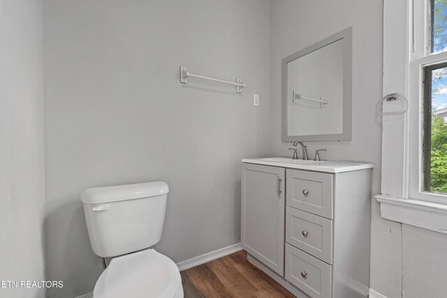 bathroom featuring toilet, vanity, wood finished floors, and baseboards