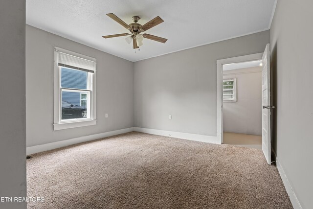 carpeted spare room with ceiling fan and baseboards