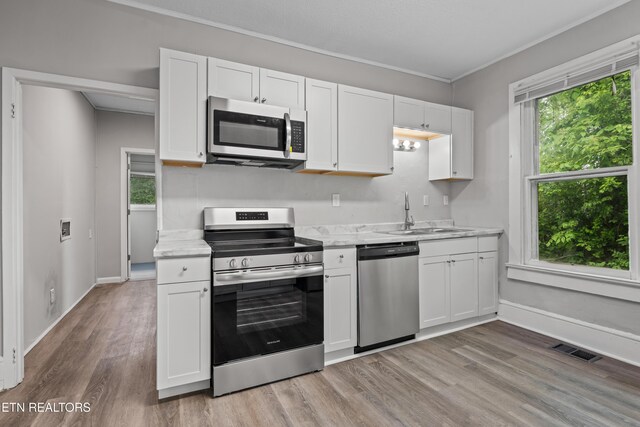 kitchen featuring white cabinetry, a sink, appliances with stainless steel finishes, visible vents, and light wood finished floors