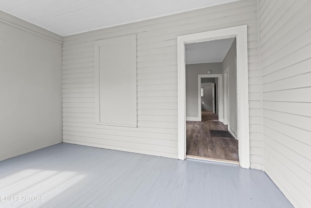 empty room with wood walls and wood finished floors