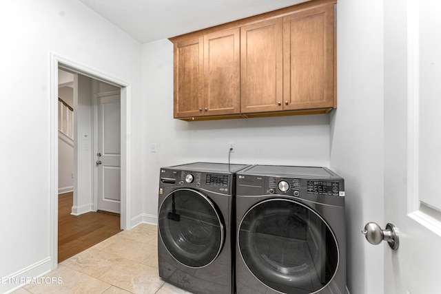 washroom with baseboards, tile patterned flooring, cabinet space, and washing machine and dryer