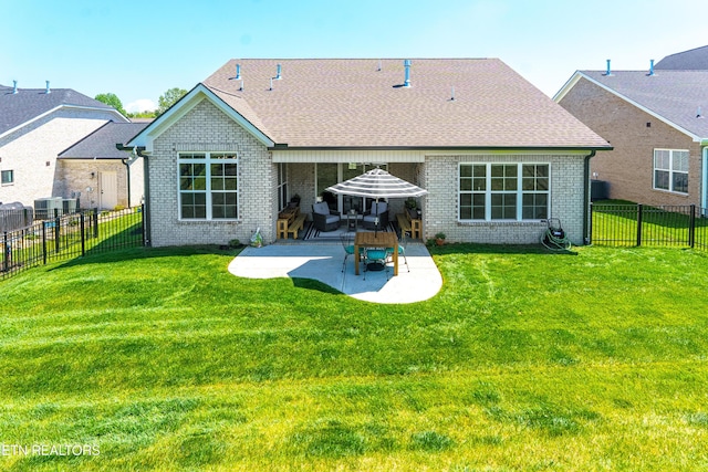 rear view of house featuring a lawn, a patio area, brick siding, a fenced backyard, and a shingled roof