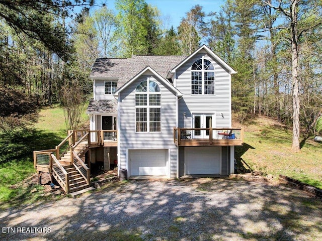 back of house with a deck, a garage, driveway, french doors, and stairs