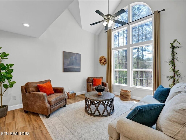 living room with high vaulted ceiling, baseboards, wood finished floors, and a healthy amount of sunlight