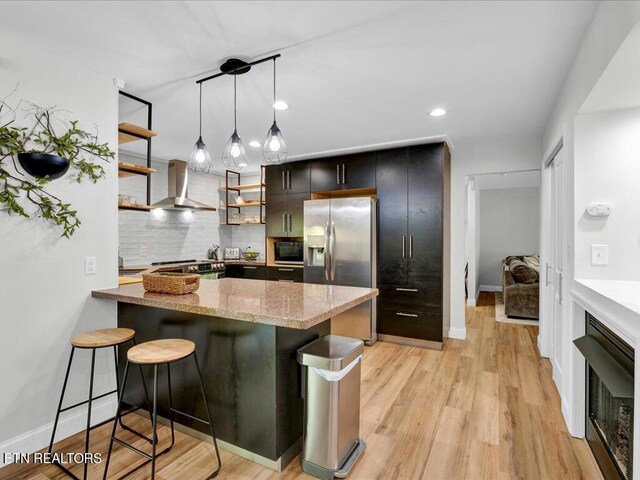 kitchen with stainless steel fridge, open shelves, wall chimney exhaust hood, a peninsula, and backsplash