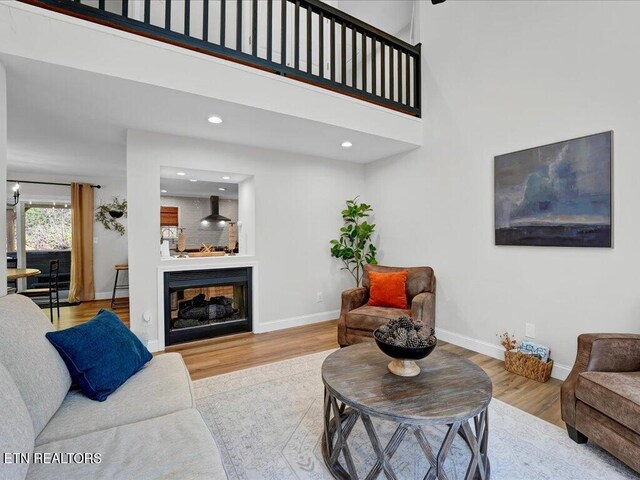 living area with baseboards, recessed lighting, wood finished floors, and a high ceiling