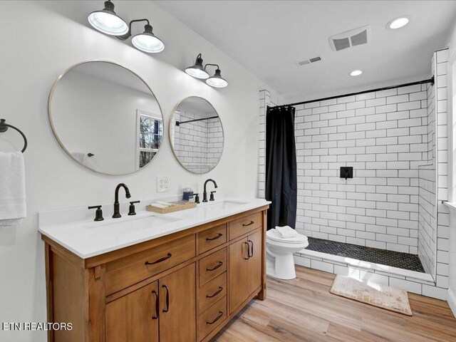 bathroom with a sink, tiled shower, and visible vents