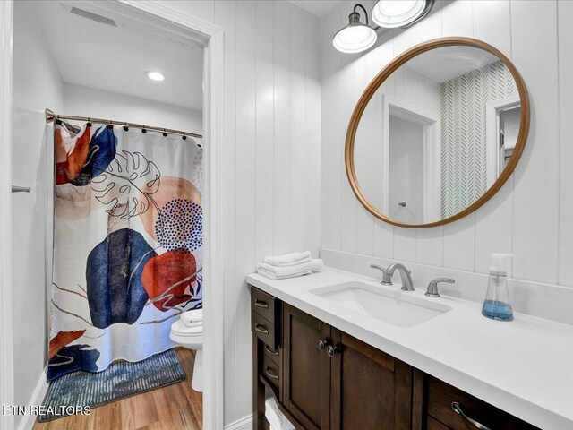bathroom featuring toilet, a shower with curtain, wood finished floors, and vanity