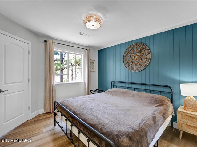 bedroom with baseboards, visible vents, and wood finished floors
