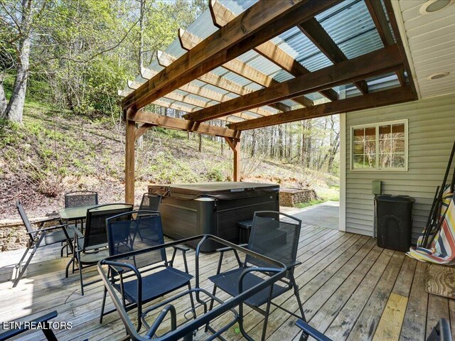 wooden deck featuring a pergola, outdoor dining area, and a hot tub