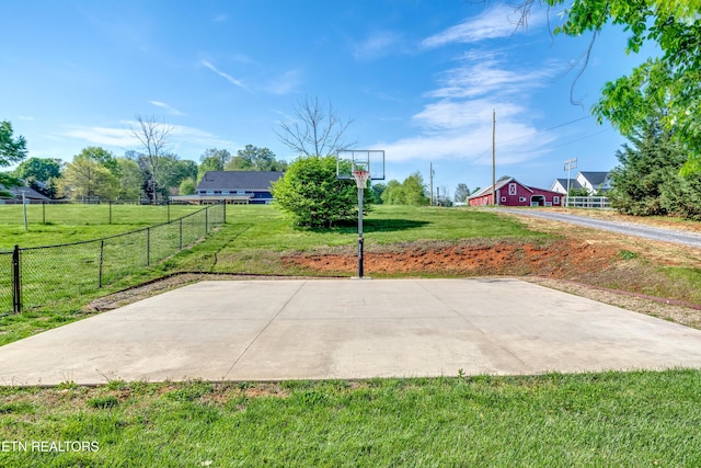 view of sport court with fence, basketball court, and a yard