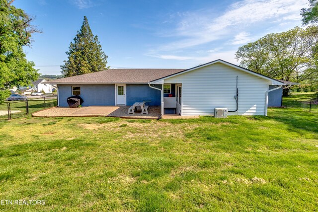 rear view of property with fence, a patio area, and a lawn