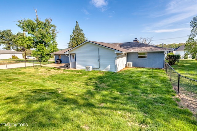 back of house with a yard, a patio area, a fenced backyard, and a chimney