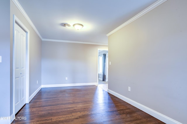 empty room with crown molding, dark wood-style flooring, and baseboards