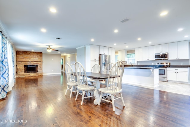 dining room with recessed lighting, a ceiling fan, a stone fireplace, and light wood finished floors