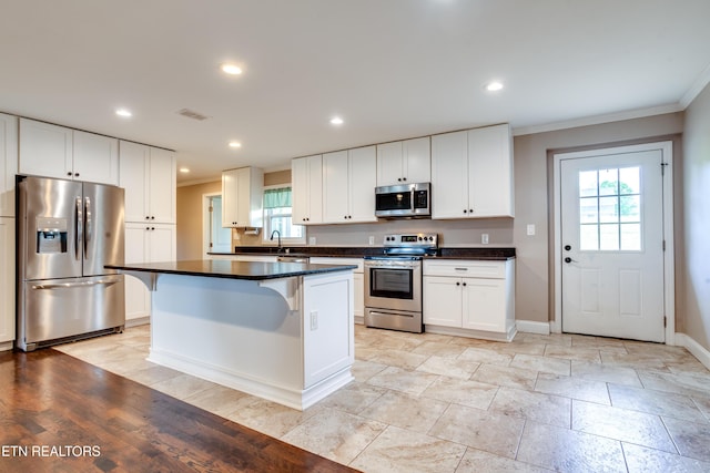 kitchen with appliances with stainless steel finishes, a healthy amount of sunlight, and ornamental molding