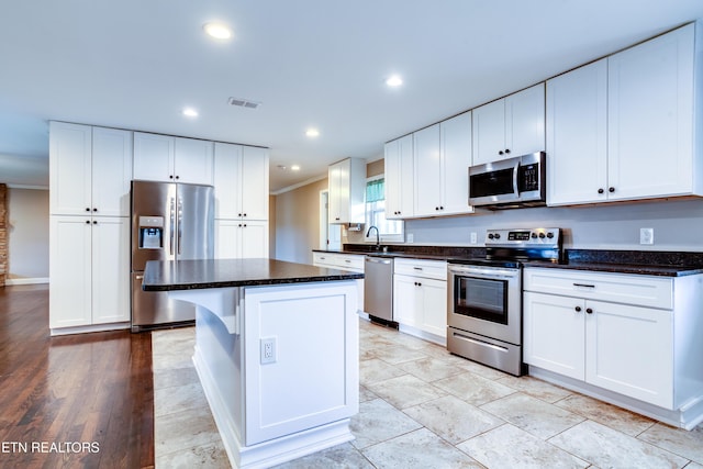 kitchen featuring crown molding, white cabinets, visible vents, stainless steel appliances, and a center island