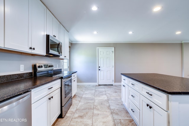 kitchen with crown molding, white cabinets, dark countertops, stainless steel appliances, and recessed lighting