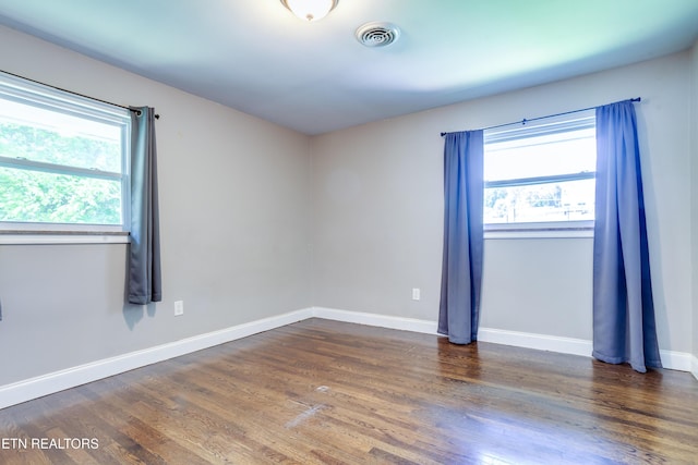 spare room with baseboards, visible vents, wood finished floors, and plenty of natural light