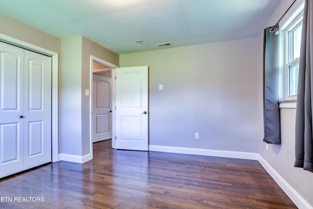 unfurnished bedroom with wood finished floors, a closet, and baseboards