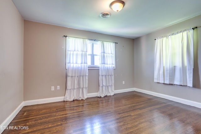 empty room featuring baseboards, visible vents, and wood finished floors