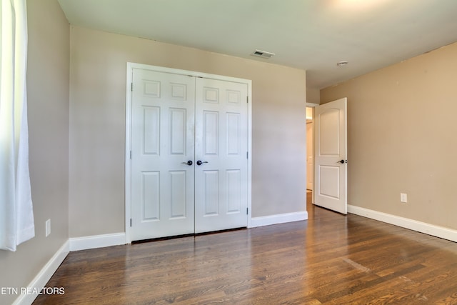 unfurnished bedroom featuring visible vents, wood finished floors, and baseboards