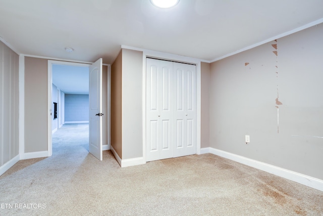 unfurnished bedroom featuring ornamental molding, a closet, baseboards, and light carpet