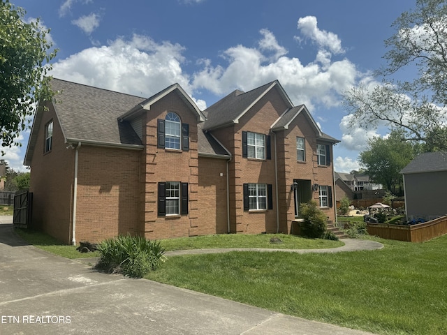 view of front of property featuring brick siding, roof with shingles, and a front lawn