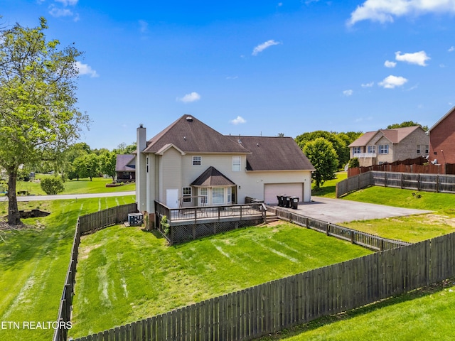 exterior space featuring aphalt driveway, a wooden deck, a fenced backyard, an attached garage, and a yard