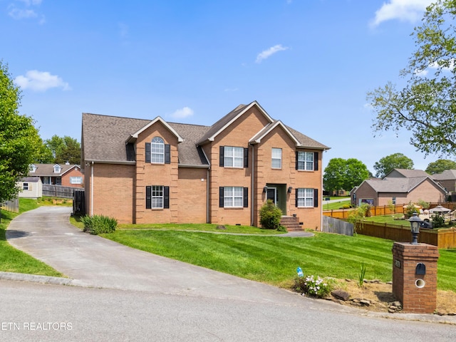 view of front of home featuring brick siding, fence, and a front lawn