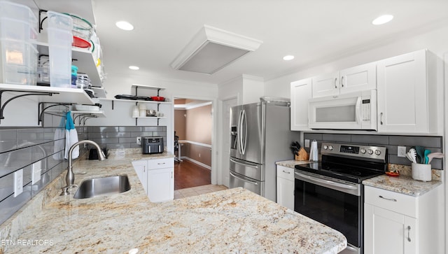 kitchen featuring crown molding, white cabinets, open shelves, appliances with stainless steel finishes, and a sink