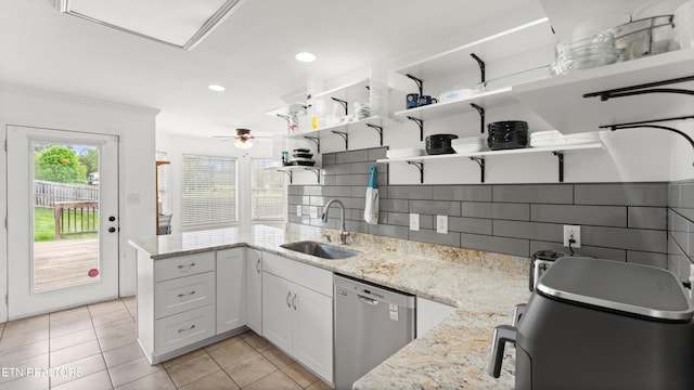 kitchen featuring light stone countertops, dishwasher, a sink, a peninsula, and light tile patterned flooring