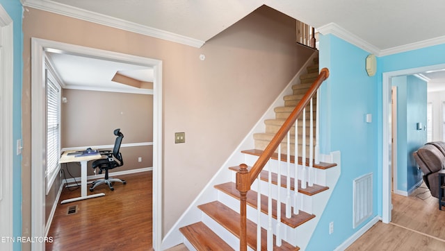stairs featuring baseboards, visible vents, ornamental molding, and wood finished floors