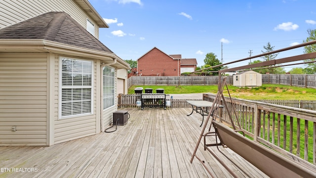 wooden terrace with an outdoor structure, a lawn, a fenced backyard, and a shed