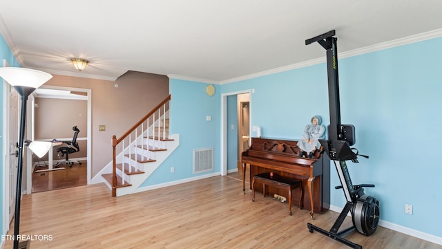 foyer with crown molding, baseboards, wood finished floors, visible vents, and stairway