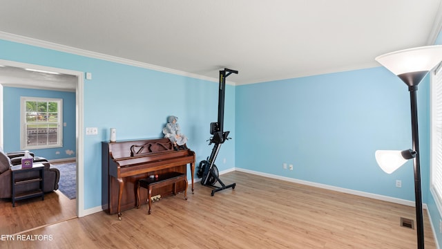 sitting room featuring baseboards, crown molding, and wood finished floors