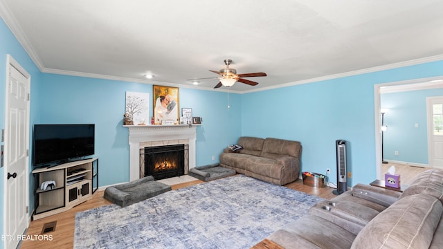 living area featuring crown molding, a fireplace with flush hearth, ceiling fan, and wood finished floors