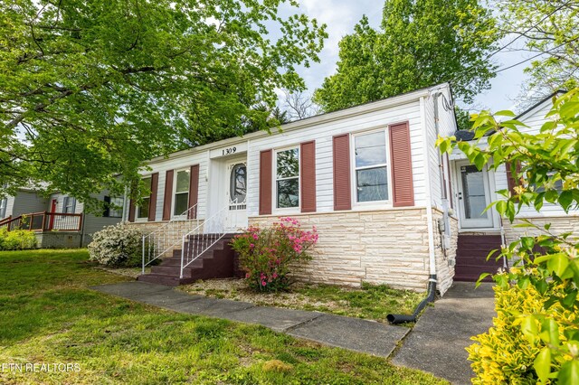 view of front of home featuring a front lawn and stone siding