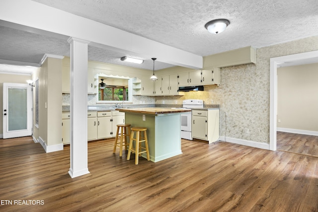 kitchen featuring electric stove, a textured ceiling, under cabinet range hood, and butcher block counters