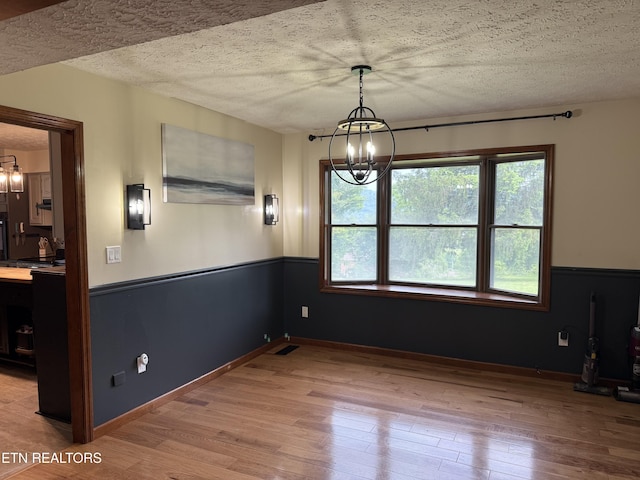 391 Underwood Grove Rd, Cumberland Gap, TN 37724 - unfurnished dining area with a chandelier, wood finished floors, and a textured ceiling