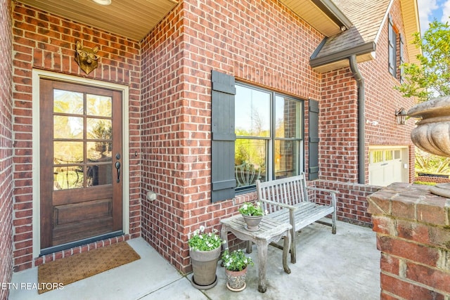 property entrance with covered porch and brick siding