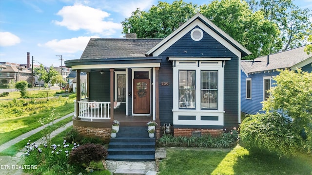bungalow-style home featuring a shingled roof, covered porch, and a chimney